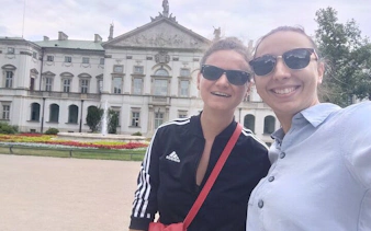 Two people smiling in front of a historic building in Warsaw's Muranów district.