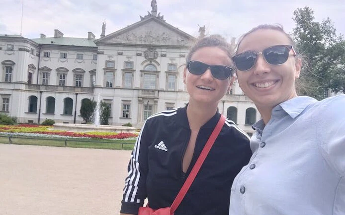 Two people smiling in front of a historic building in Warsaw's Muranów district.