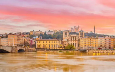 Lyon skyline with Basilica of Notre-Dame de Fourvière at sunset, viewed from the Saône River.