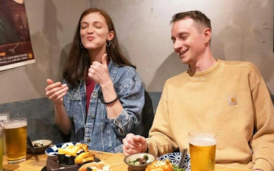 Two people enjoying sushi and drinks at a local eatery in Shinjuku, Tokyo.