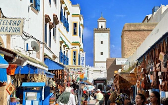 Essaouira market street with shops and mosque tower, Marrakech day trip.