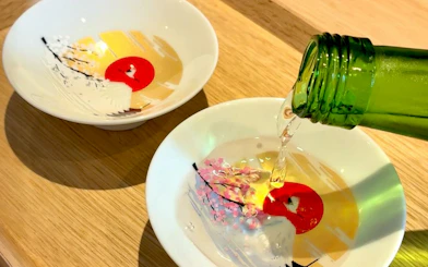 Pouring sake into decorative cups during a Kyoto sake tasting experience.
