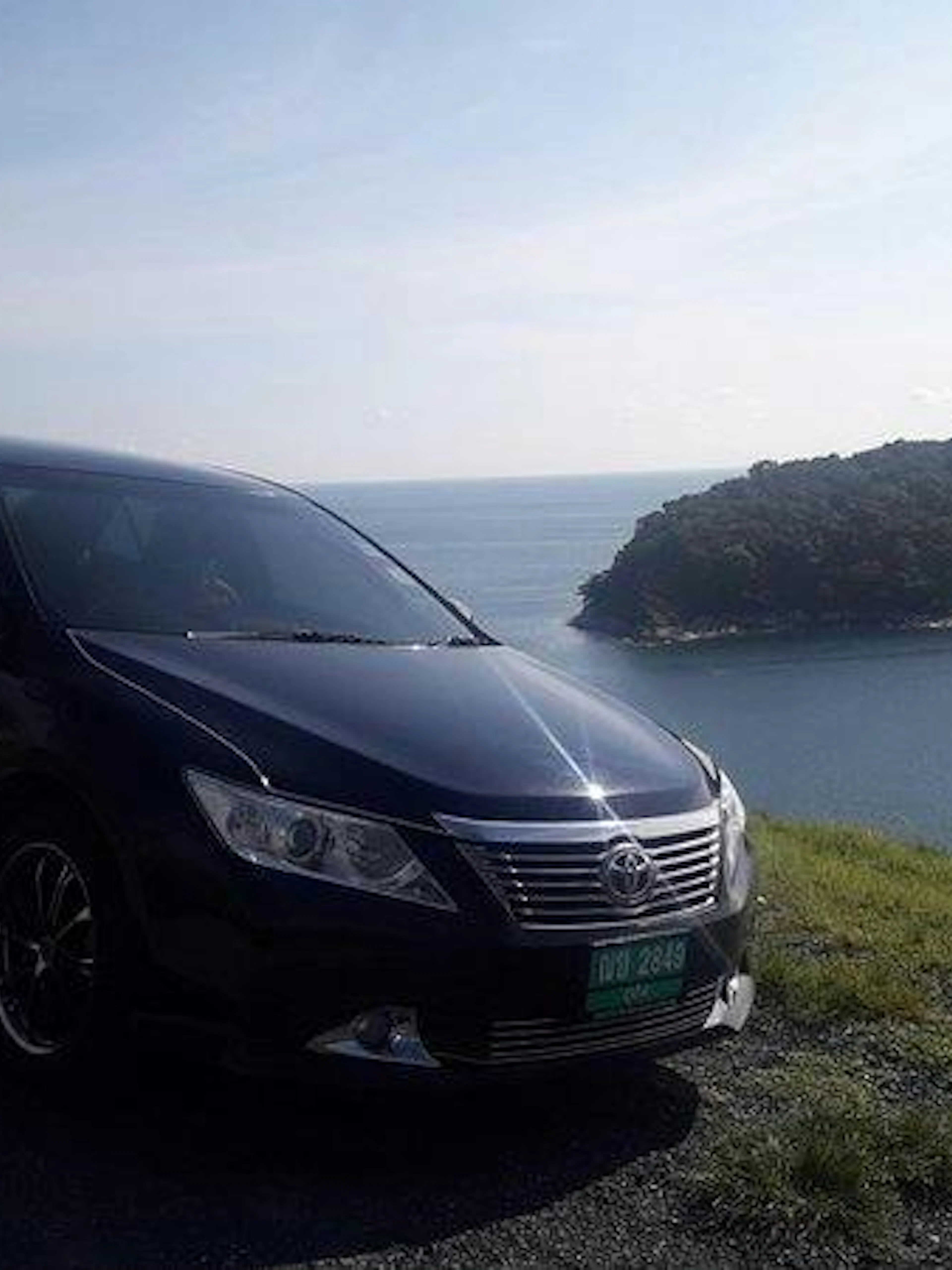 Car parked by the coast with ocean view, Phuket Airport Transfers.