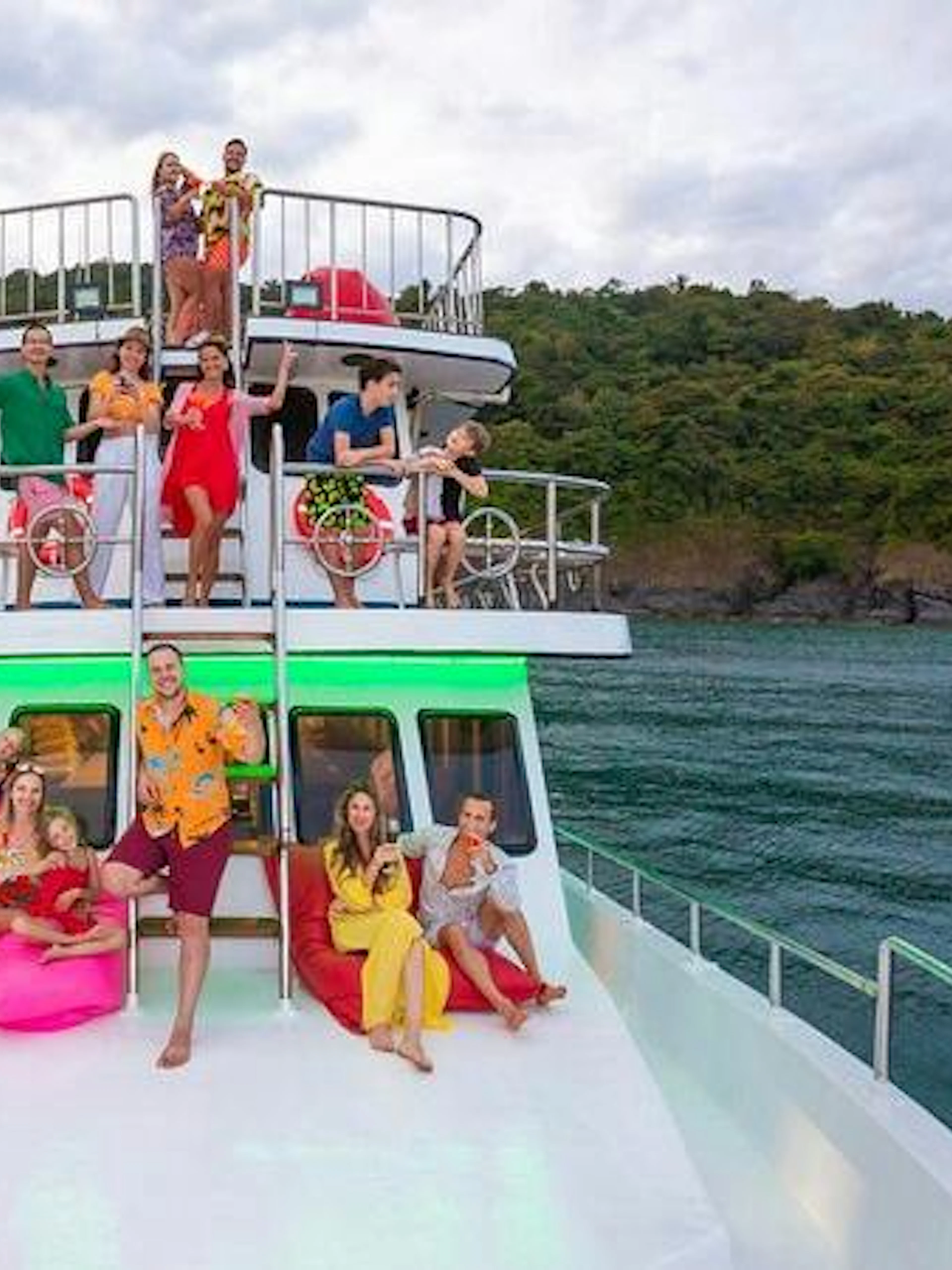 Group enjoying a cruise on a boat near Phuket with lush hills in the background.