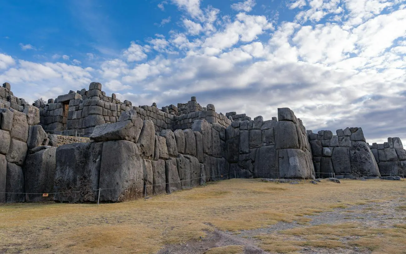 Sacsayhuamán stone walls under a cloudy sky in Cusco, Peru.