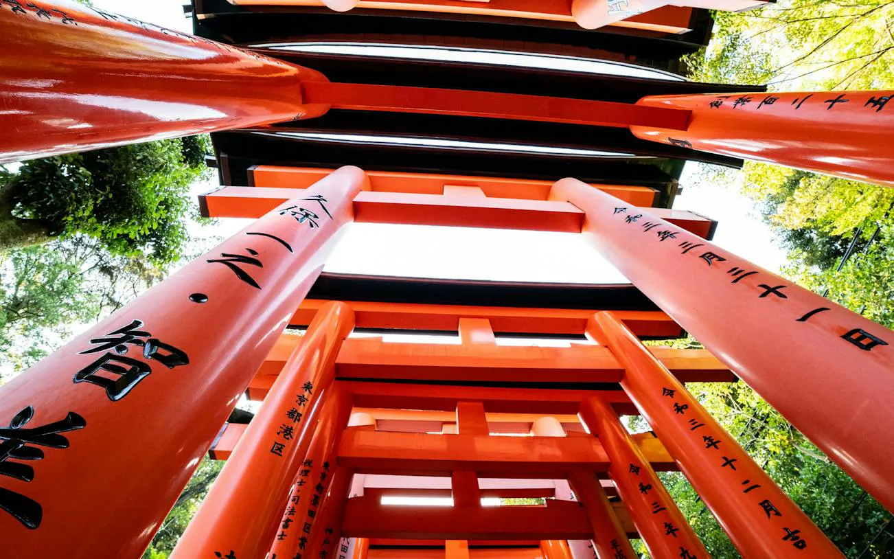 Red torii gates at Fushimi Inari Shrine, Kyoto, viewed from below with inscriptions.
