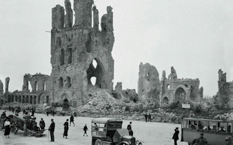 Ruins of Ypres Cloth Hall post-WWI, visitors and vintage vehicles in foreground, Flanders Fields tour.