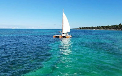 Sailing catamaran on turquoise waters, Punta Cana, with distant shoreline.