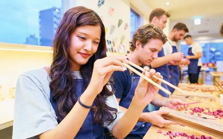 Participants crafting chopsticks with kanji engraving at a workshop in Osaka.