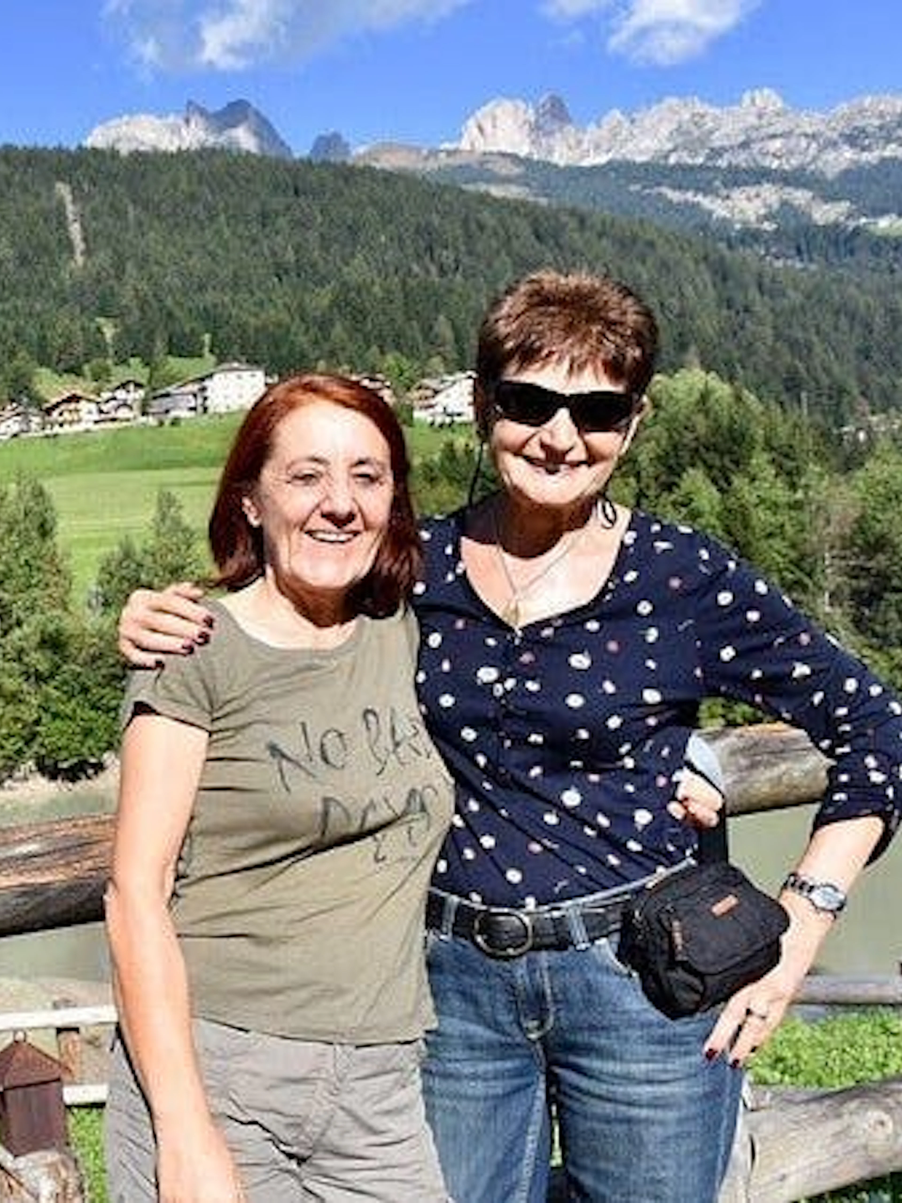 Two people smiling with Dolomites mountains and lush greenery in the background, Verona tour.