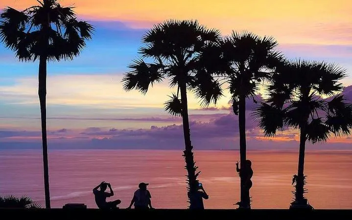Sunset view with palm trees and tourists at Promthep Cape, Phuket.