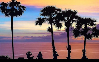 Sunset view with palm trees and tourists at Promthep Cape, Phuket.