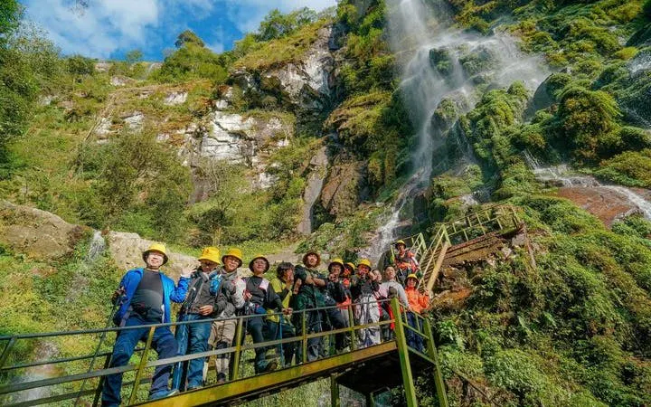 Group on a bridge near Queen Bee Waterfall during Sapa motorbike and jungle trek tour.