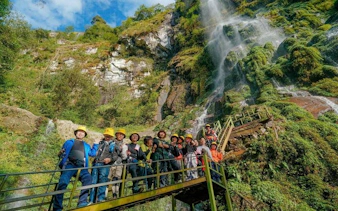Group on a bridge near Queen Bee Waterfall during Sapa motorbike and jungle trek tour.