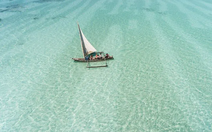 Traditional dhow sailing on clear waters in Zanzibar, Tanzania.