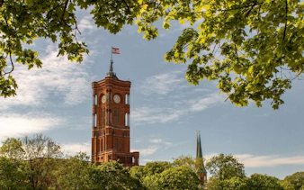 Red Town Hall tower in Berlin surrounded by trees, part of the Old Town self-guided audio walk.