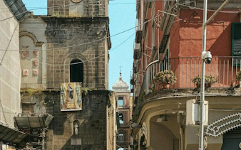 Historic buildings along Spaccanapoli street in Naples, featuring a church facade and balcony.
