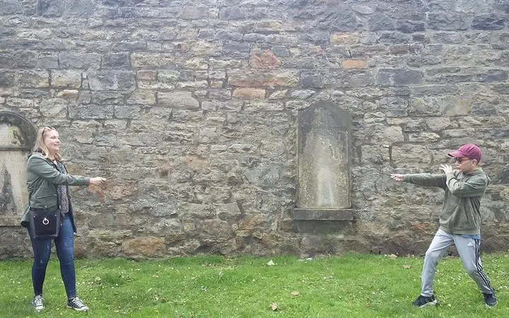 Two people reenacting a wizard duel in front of a historic stone wall in York.