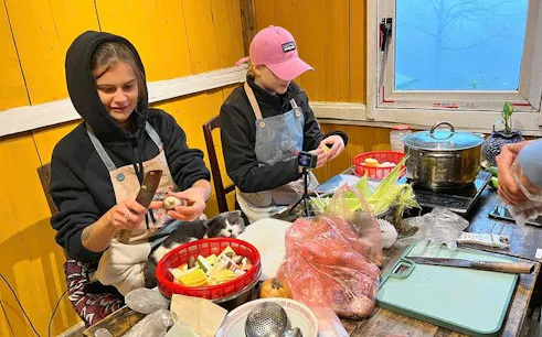 Local chef guiding participants in a pho noodle soup cooking class, preparing ingredients at a wooden table.