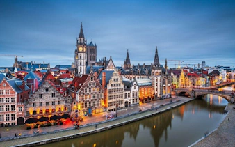 Historic buildings along the Graslei canal in Ghent, Belgium, at dusk.