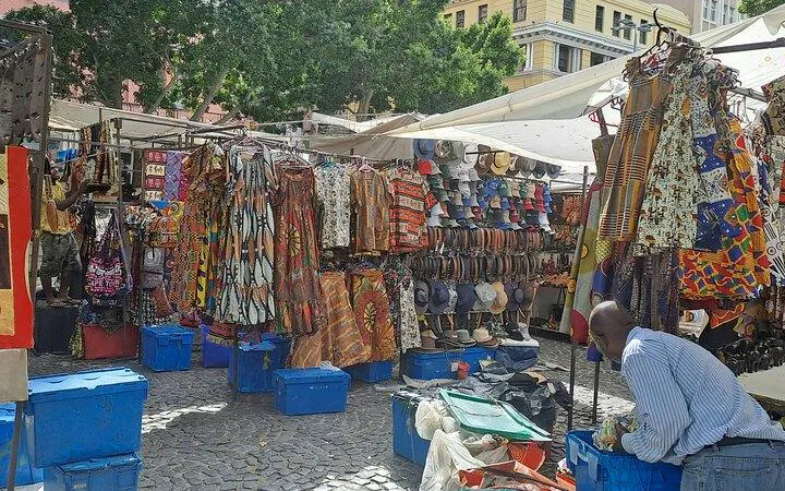 Outdoor market with colorful clothing and hats on display, Cape Town Private Shopping Tour.