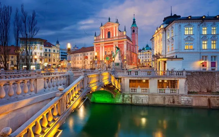 Franciscan Church and Triple Bridge in Ljubljana at dusk on self-guided walking tour.