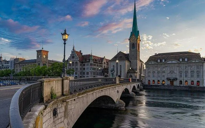 Bridge over Limmat River with Fraumünster Church in Zurich at sunset.