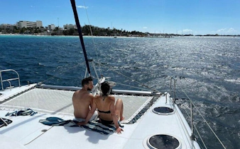 Couple relaxing on catamaran deck during Isla Mujeres tour with ocean view.