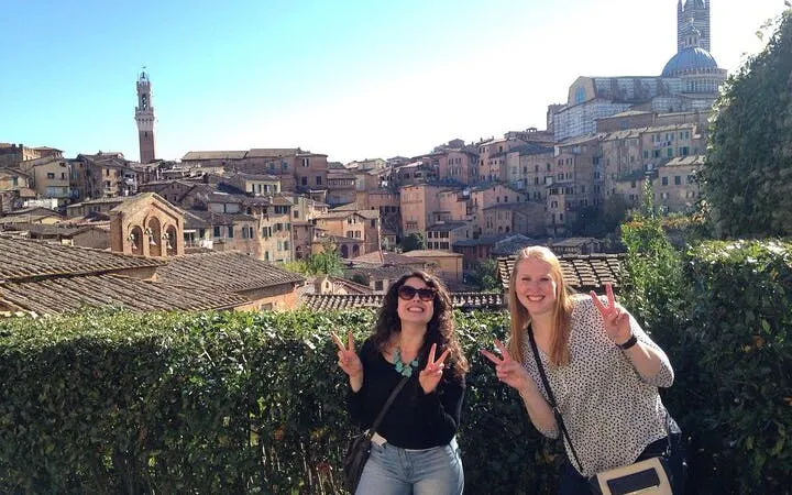 Two tourists in Siena with cityscape and Torre del Mangia in the background.