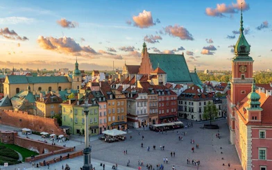 Warsaw Old Town Square with colorful buildings and Royal Castle tower.