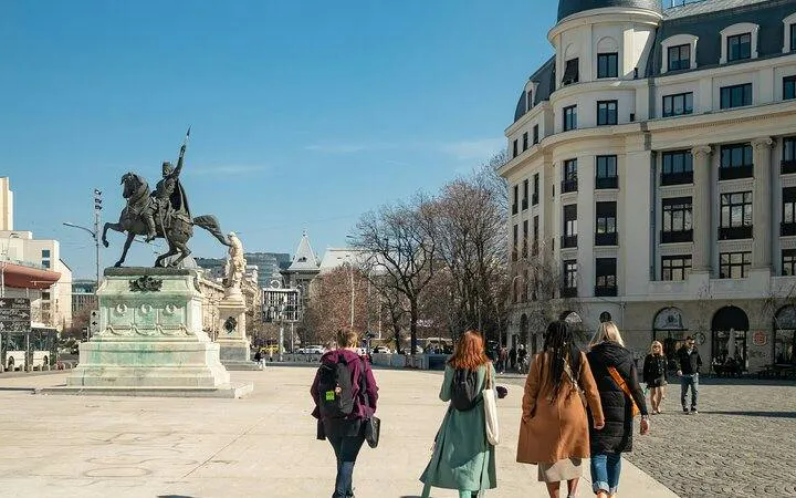 Walking tour group near equestrian statue in Bucharest Old Town.