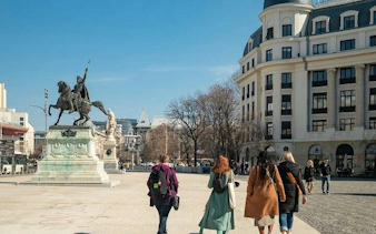 Walking tour group near equestrian statue in Bucharest Old Town.
