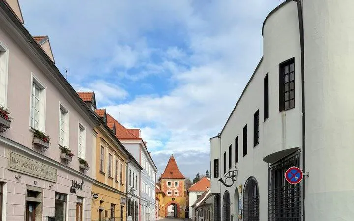 Street view of Cesky Krumlov with historic buildings and a distant tower.