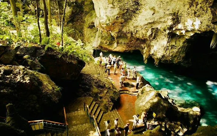 Tourists exploring Tres Ojos Cenote cave with turquoise water in Santo Domingo, part of guided tour from Punta Cana.