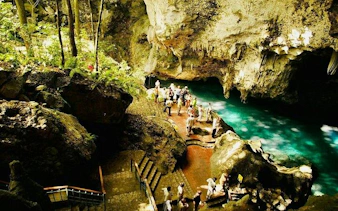 Tourists exploring Tres Ojos Cenote cave with turquoise water in Santo Domingo, part of guided tour from Punta Cana.
