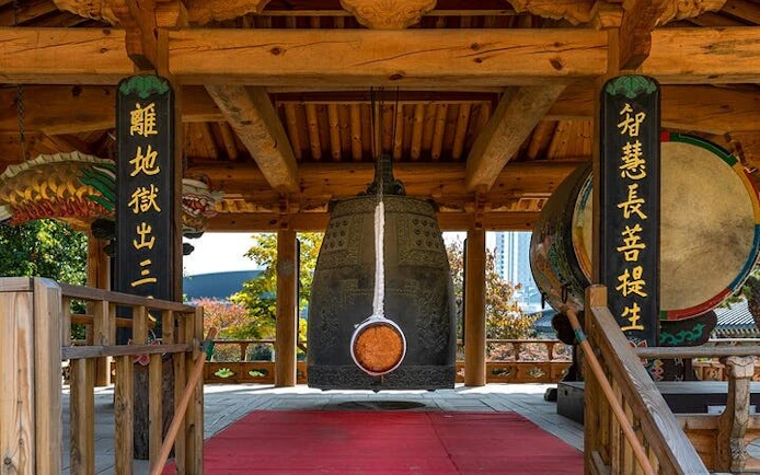 Traditional Korean temple bell under wooden pavilion, part of Korea private car and driver city tour.