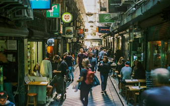 Crowded Melbourne laneway with cafes and shops, part of self-guided audio walking tour.