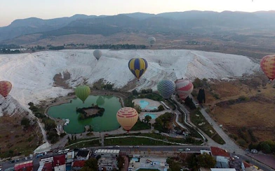 Hot air balloons over Pamukkale travertines and Hierapolis, Turkey.