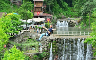 Ziplining over a waterfall in Sapanca, Turkey, with lush greenery and a scenic backdrop.