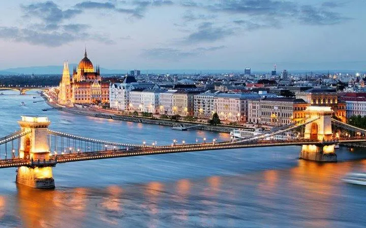 Chain Bridge and Budapest Parliament along the Danube River at dusk.