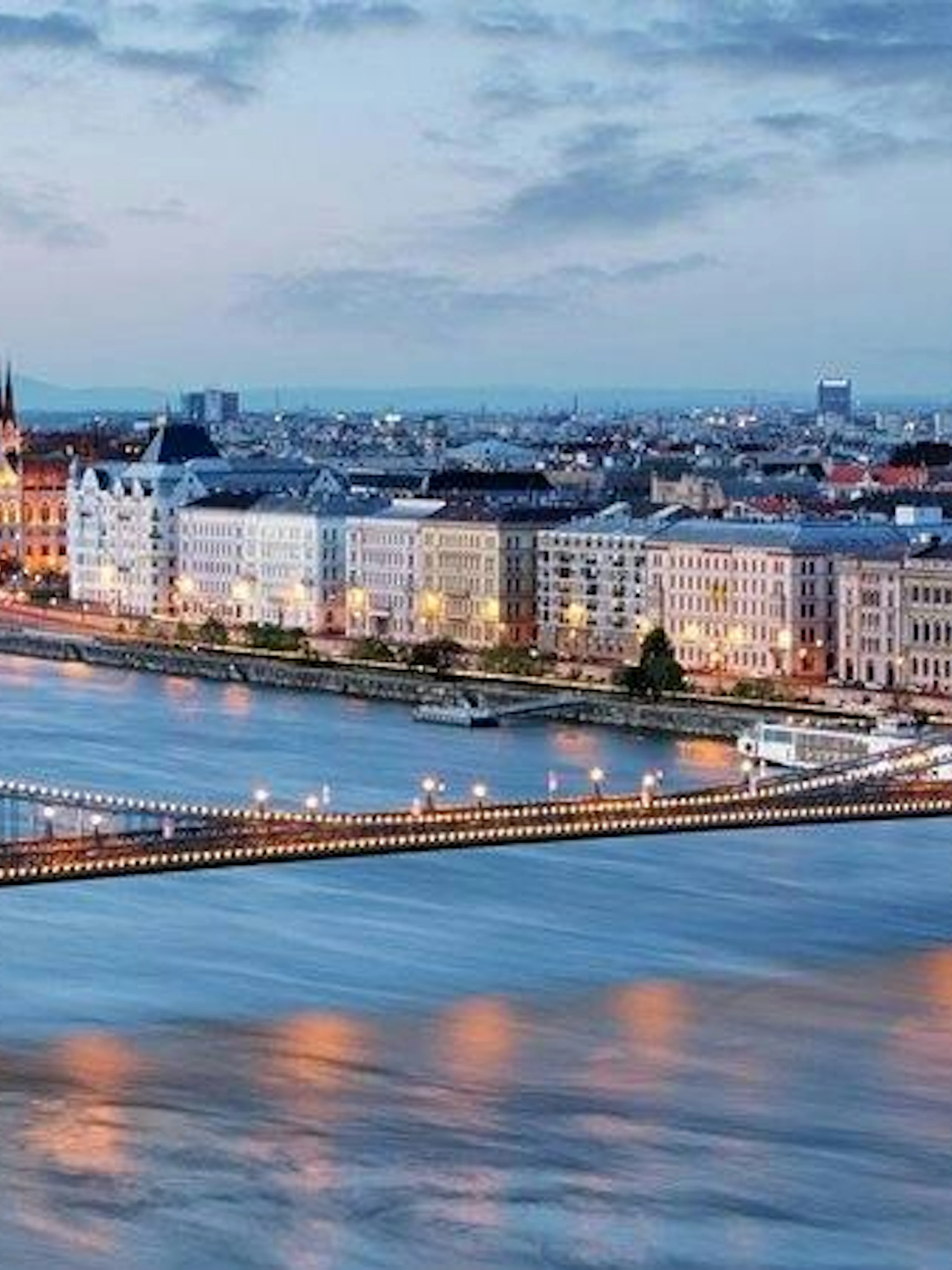 Chain Bridge and Budapest Parliament along the Danube River at dusk.