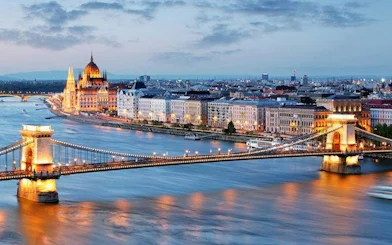 Chain Bridge and Budapest Parliament along the Danube River at dusk.