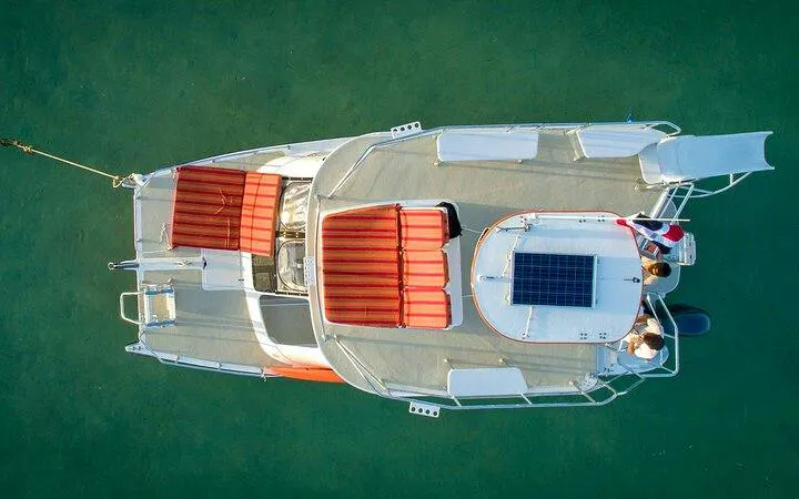 Catamaran with red seating on clear water, Punta Cana cruise with snorkeling and floating bar.