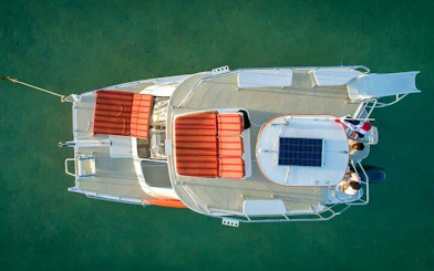 Catamaran with red seating on clear water, Punta Cana cruise with snorkeling and floating bar.