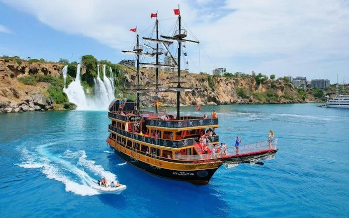 Pirate-themed boat near Lower Duden Waterfall, Antalya, with tourists enjoying the cruise.