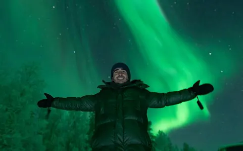 Person enjoying Northern Lights display in Sirkka during small-group tour from Ylläs or Levi.