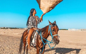 Horse riding in Sharm El Sheikh desert with a view of distant buildings.