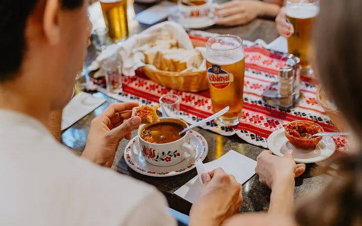Dining with traditional Hungarian goulash and beer on Budapest food tour.