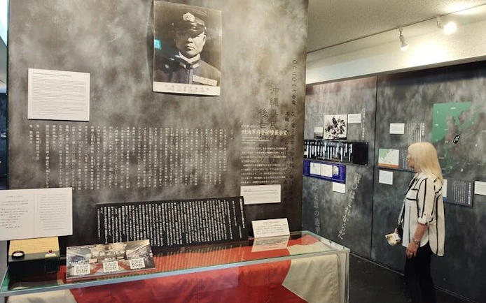 Naha WWII Navy Underground HQ exhibit with historical documents and visitor.