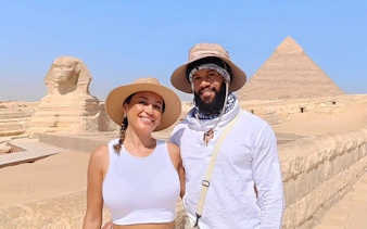 Tourists at Giza Pyramids with Sphinx in background, Egypt.